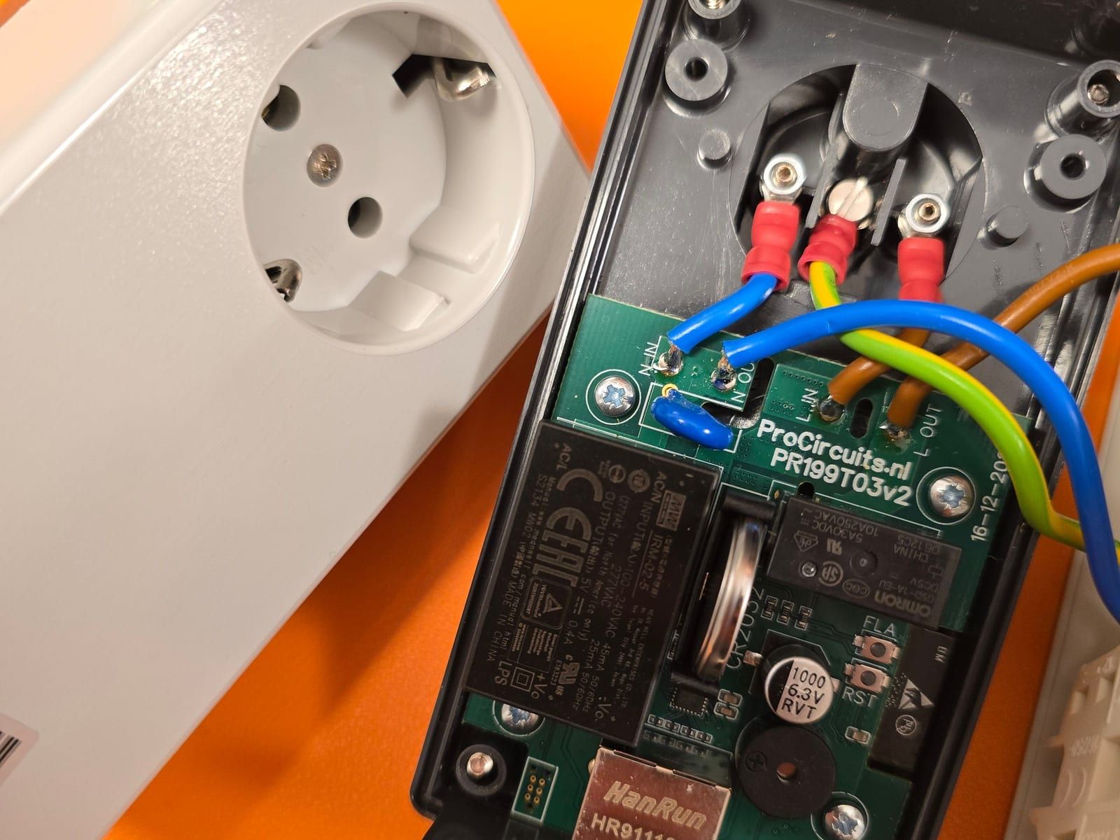Geopende tussenstekker met een groene print van ProCircuits die het stroomverbruik meet